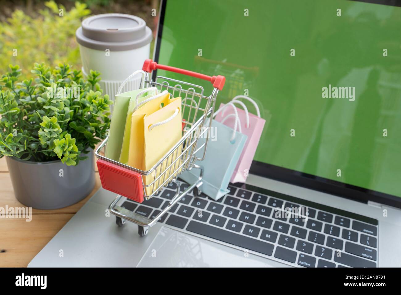 Mehrfarbige kleine Papiertüte in einem winzigen Trolley, Online Shopping Konzept. Stockfoto