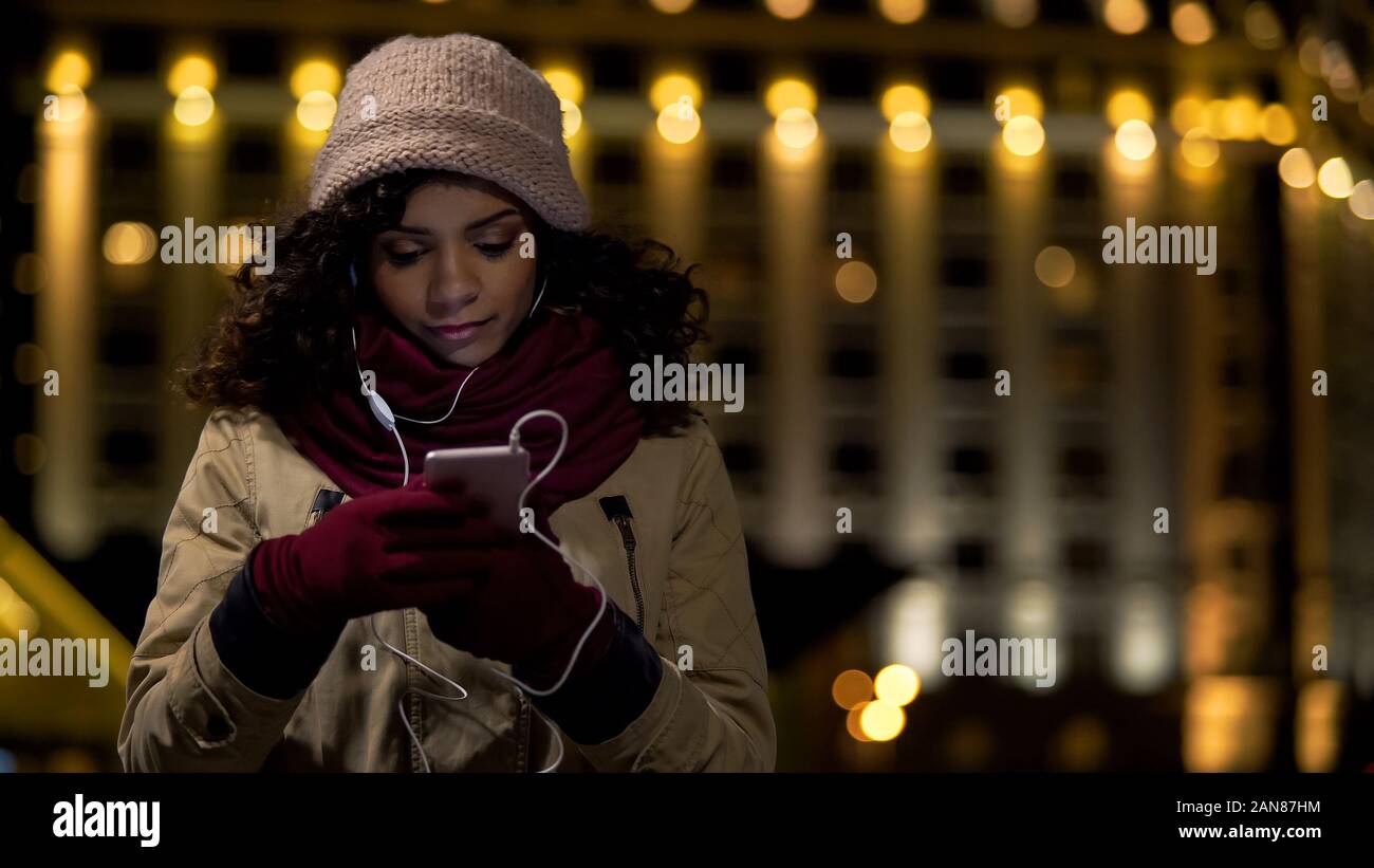 Lady scrollen Telefon und Musik zu hören, auf der Suche nach internet shop online Stockfoto