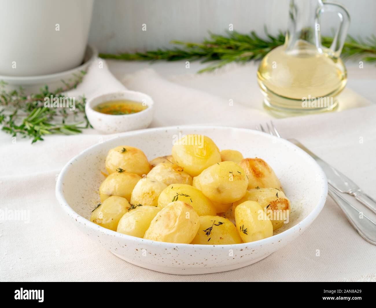 Im Ofen gebacken mit Gewürzen runden ganze Knollen der Kartoffel in der Platte auf White Background, golden mit Kruste, Seitenansicht Stockfoto