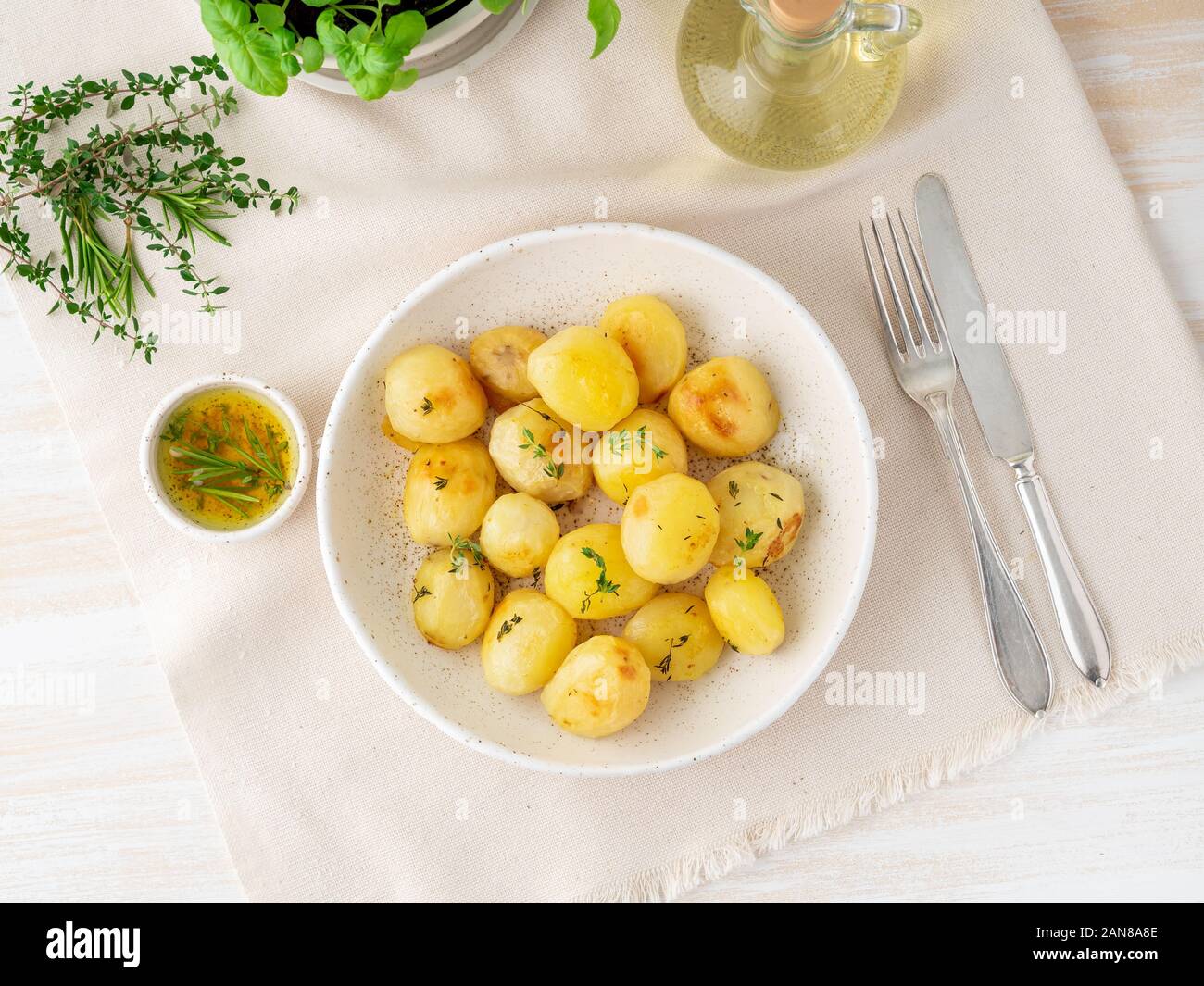 Im Ofen gebacken mit Gewürzen runden ganze Knollen der Kartoffel in der Platte auf White Background, golden mit Kruste, Ansicht von oben Stockfoto