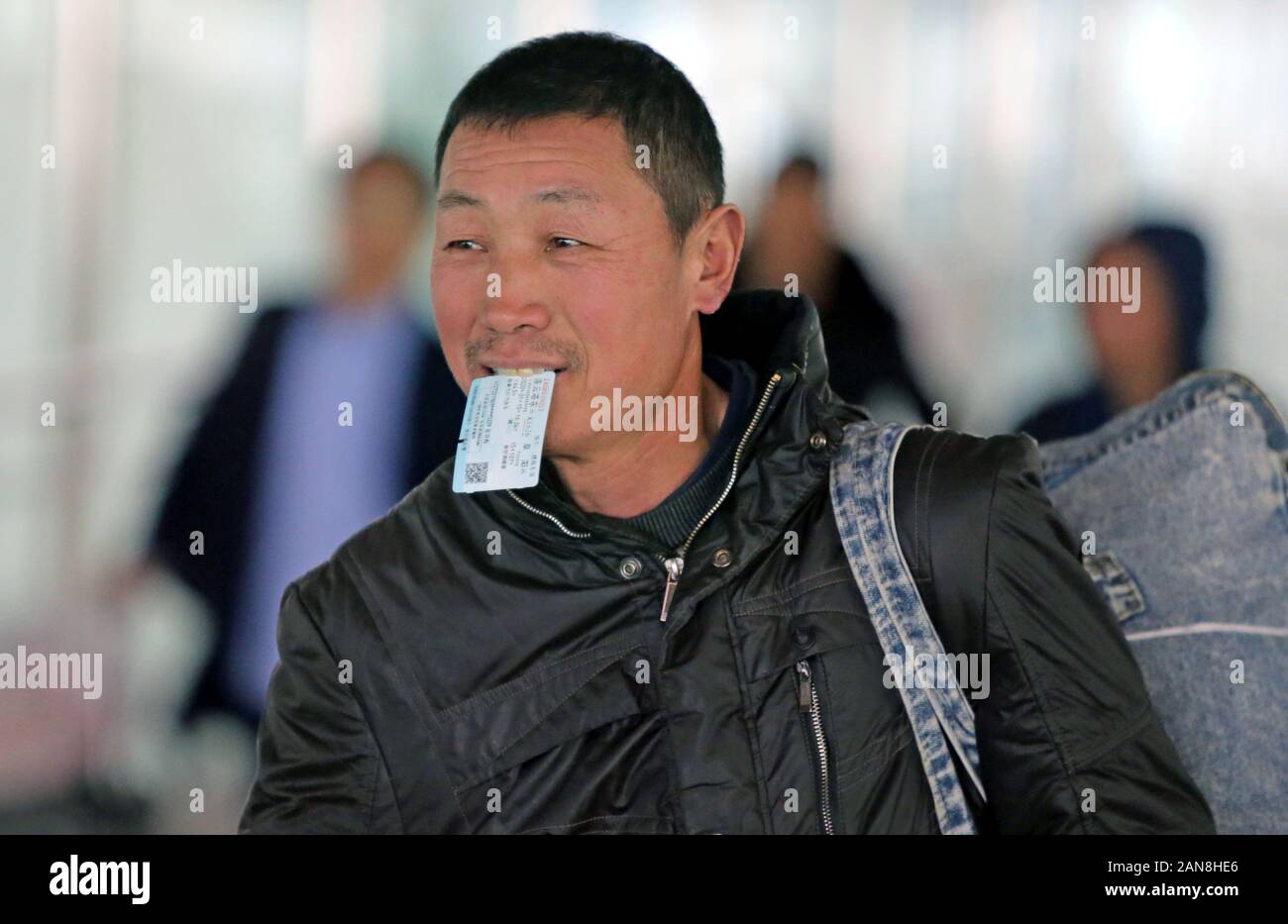 Ein chinesischer Wanderarbeiter mit seiner Fahrkarte im Mund Spaziergänge mit dem Zug zurück nach Hause für die kommenden chinesischen neuen Jahres zu gehen während der jährlichen zu Stockfoto