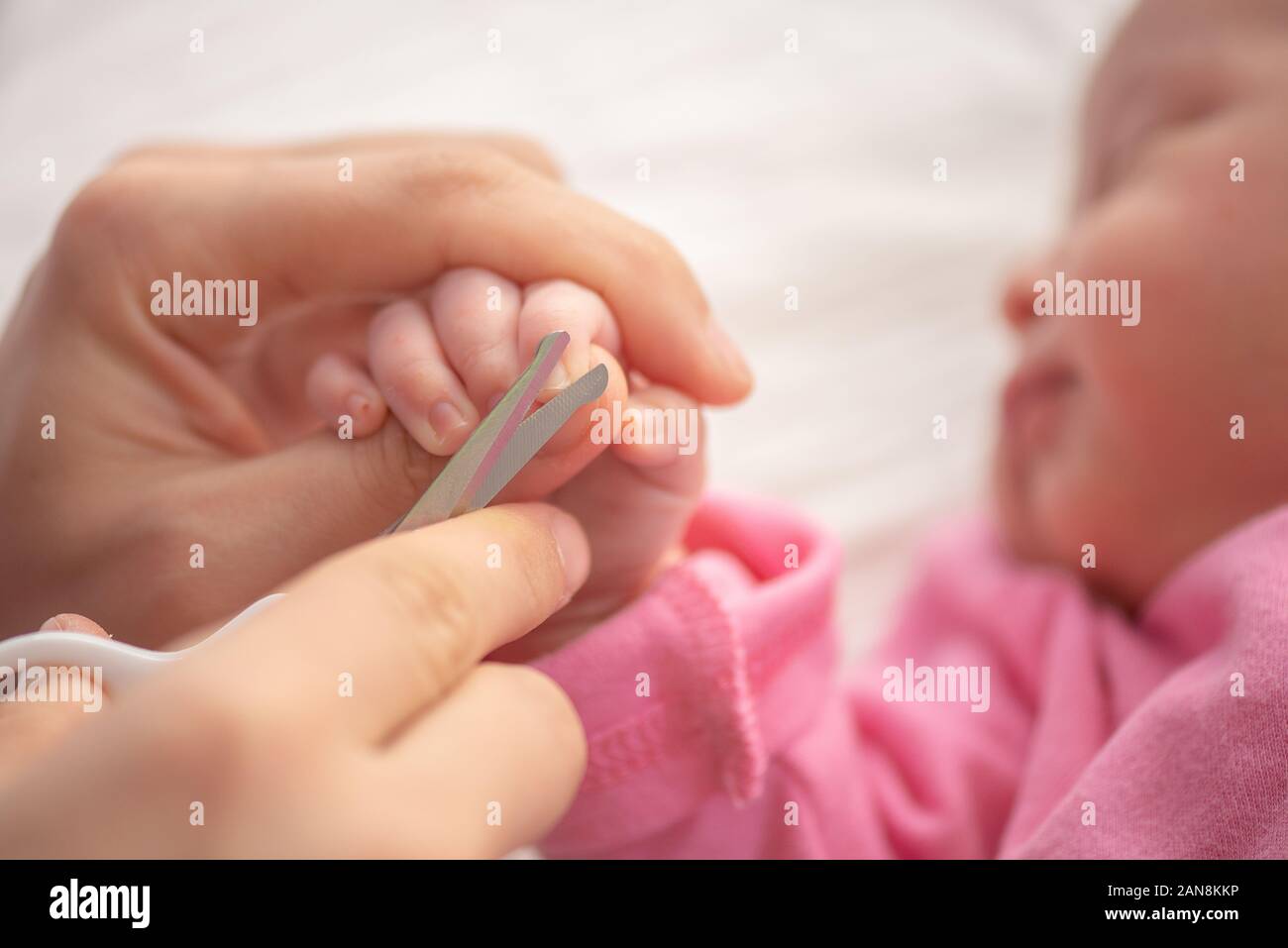 Baby, Fingernägel schneiden, während seine Mutter mit einer Schere zu schlafen. Pflege ein Kind. Stockfoto