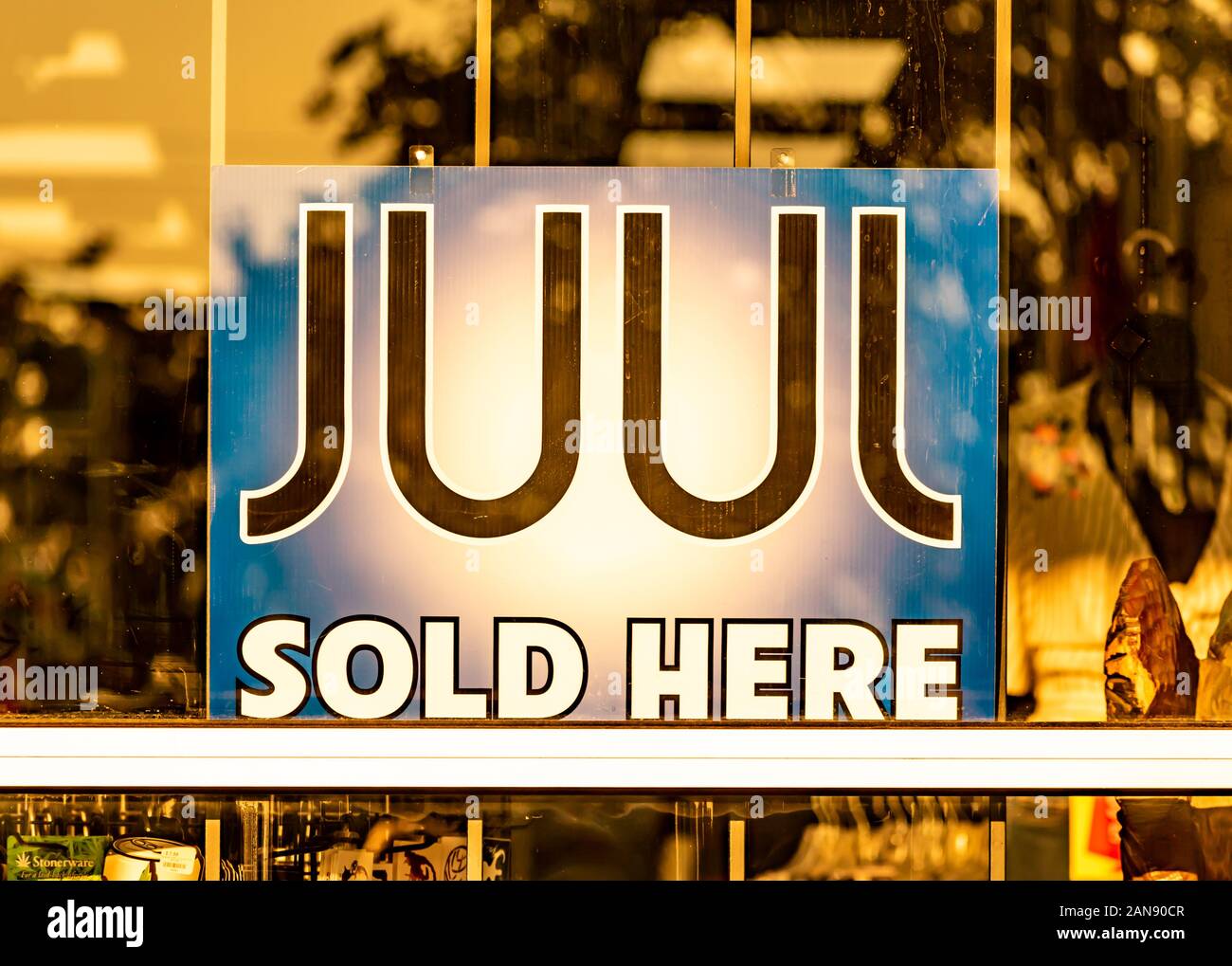 Charlotte, NC/USA - 26. Juli 2019: Horizontaler Abschluss der Schaufensteranzeige mit der Aufschrift "JUUL Sold Here" auf undurchsichtigem Schild mit goldenen Fensterreflexionen. Stockfoto