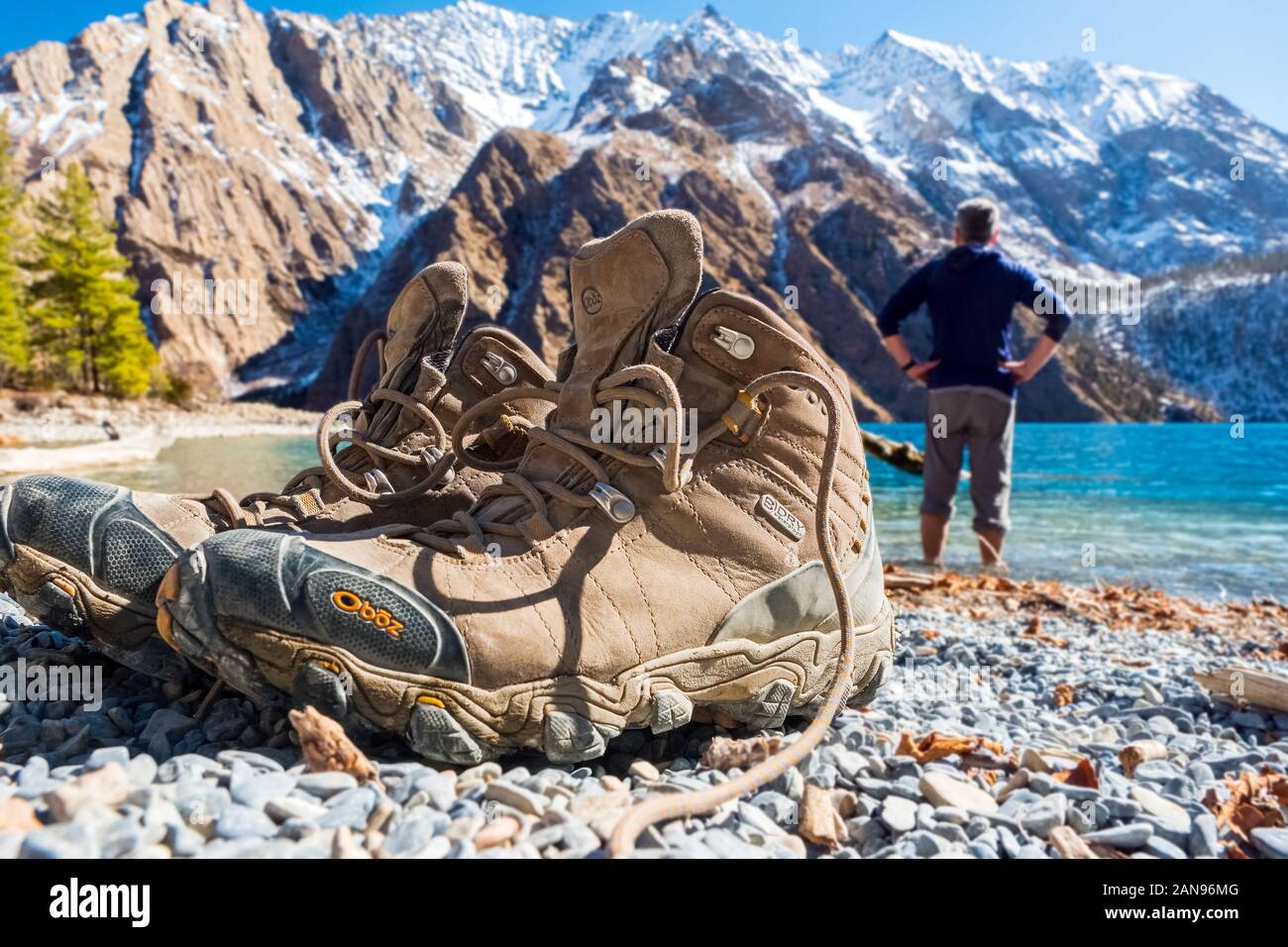 Paar Fuß-/Wanderstiefel am Ufer des Phoksundo Lake, Dolpo, Nepal. Trekker kühlt seine Füße im See. Stockfoto