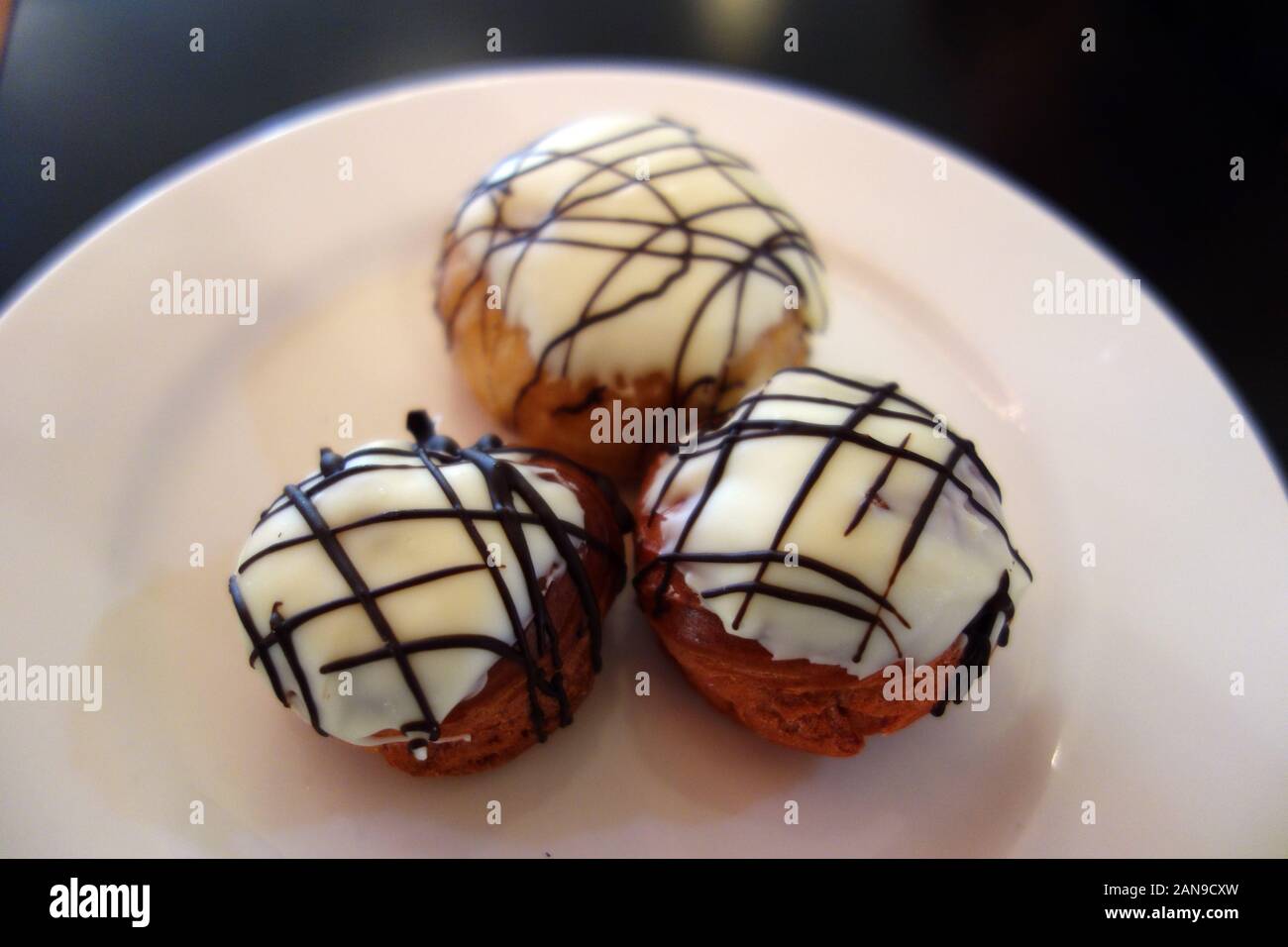 Drei weiße Schokolade Profiteroles Beträufelt mit dunkler Schokolade & gefüllt Creme Patissiere in das Buffet im Azul Beach Hotel, Puerto Morelos Stockfoto