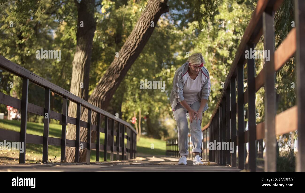 Frau mittleren Alters plötzlich Gefühl Krampf im Bein beim Laufen, Gesundheit Stockfoto