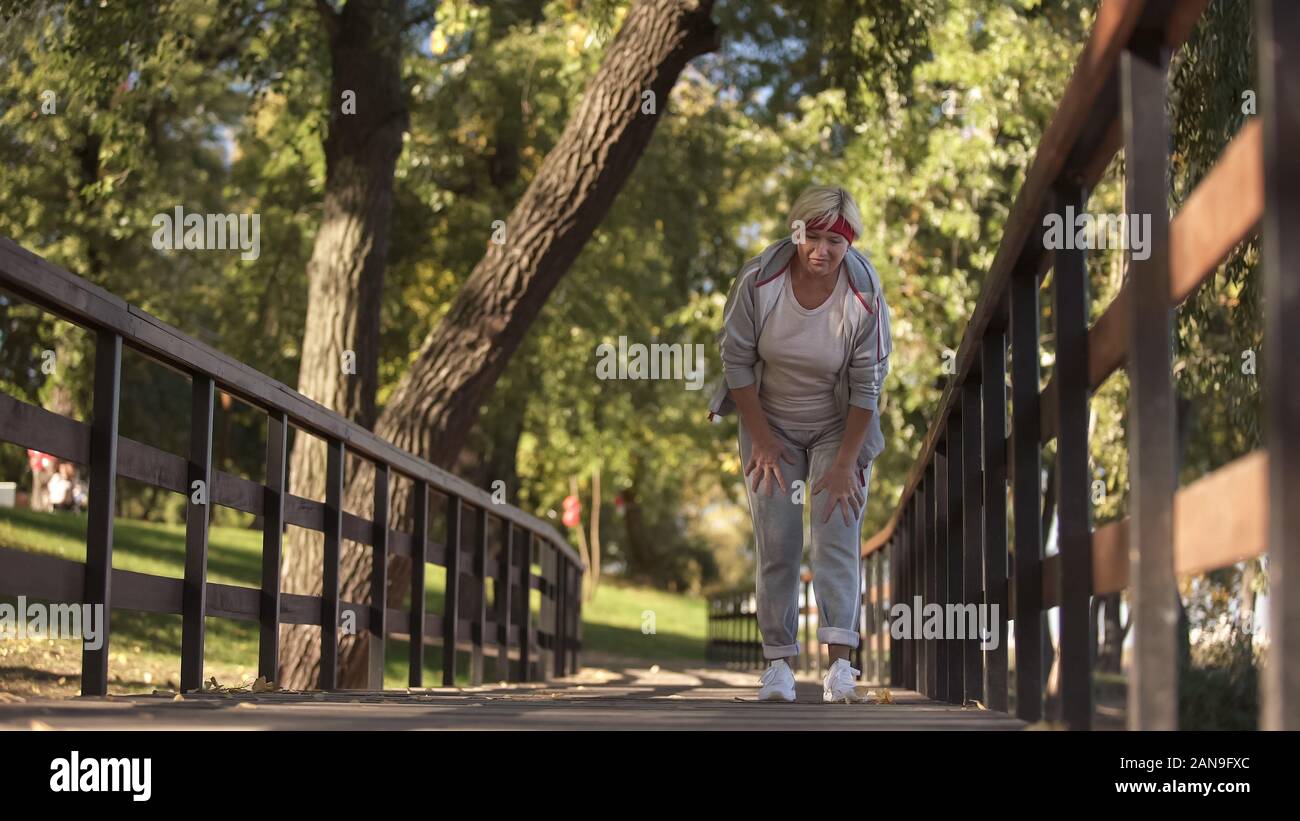 Sportliche ältere Frau hält ihre Knie Gefühl starken Schmerzen beim Joggen, Gesundheit Stockfoto