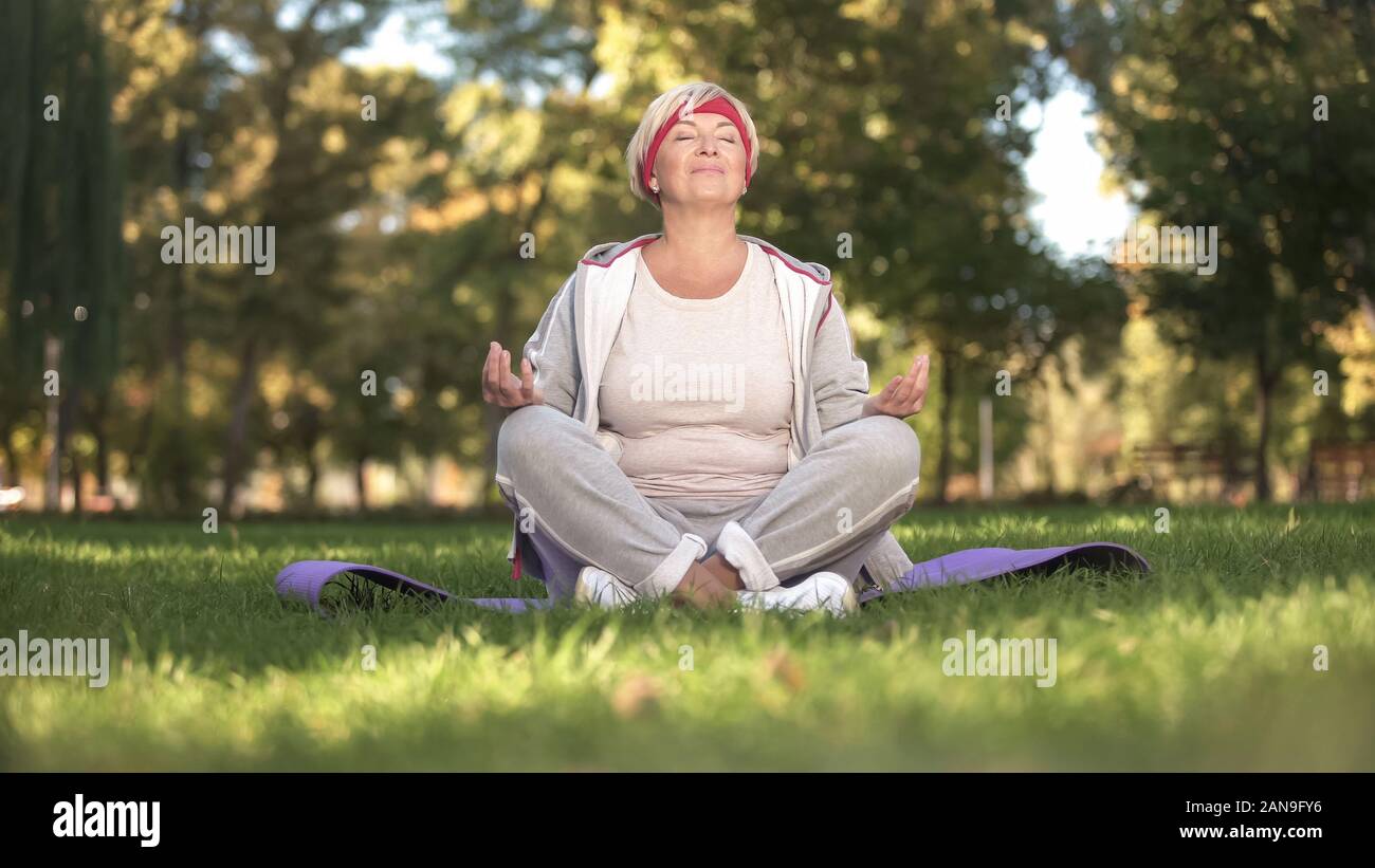 Mittleres Alter Frau, tief zu atmen und Meditieren sitzen in Lotus Position Stockfoto