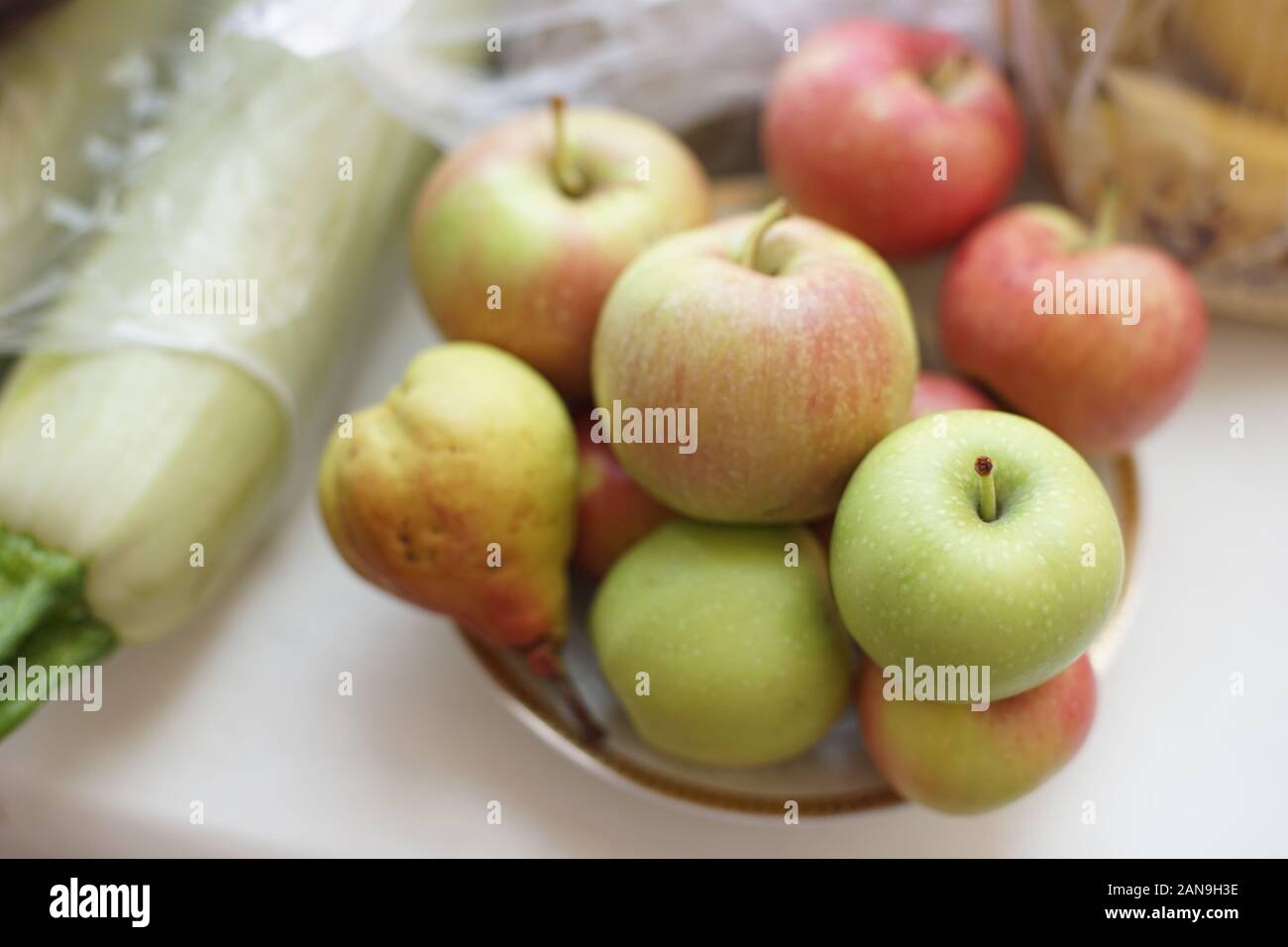 Ganze Äpfel auf einer Platte und Zucchini auf dem Tisch. Stockfoto