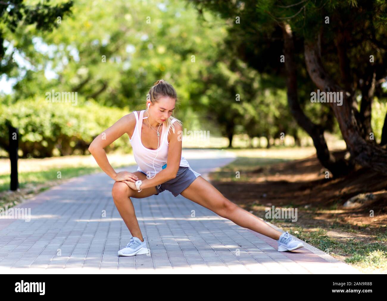 Junge Sportlerin Stretching und Vorbereitung der Wiedergabe der Musik auf mobile App ausführen zu können. Stockfoto
