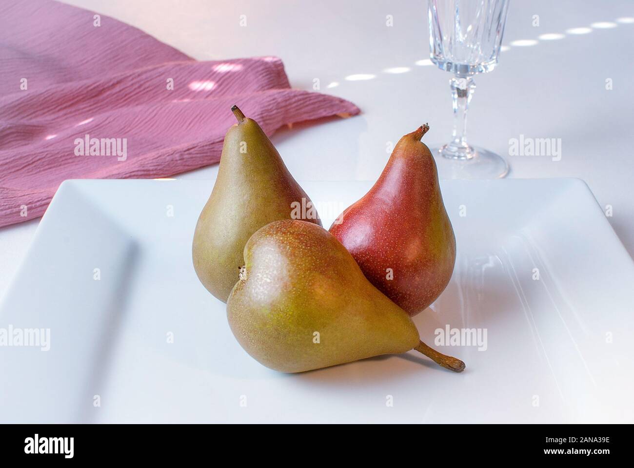 Drei elegante Birnen auf eine quadratische Platte. Stockfoto