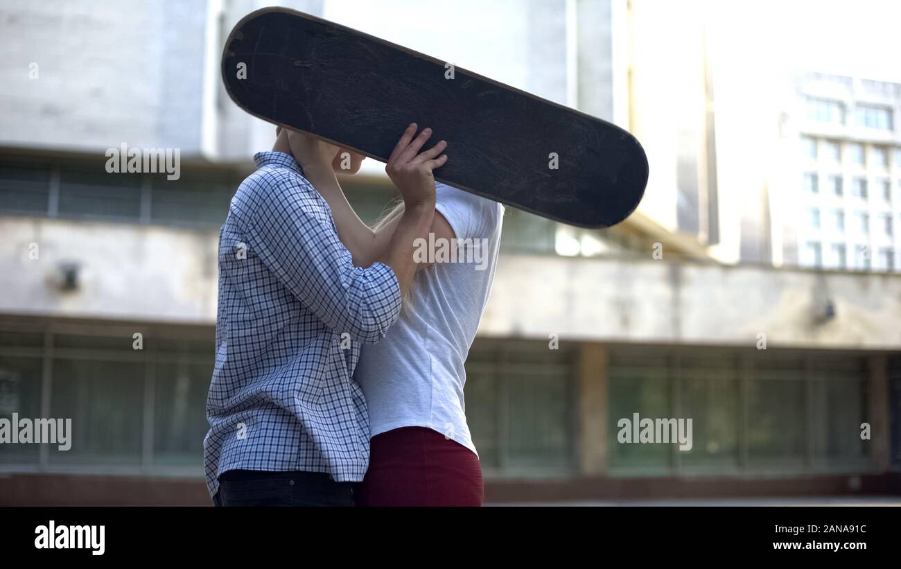 Paar Skateboarder küssen, Gesichter hinter Bord versteckten, Jugend Subkultur Stockfoto