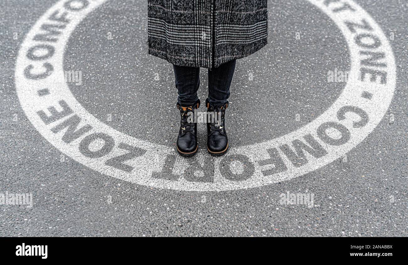 Hohen winkel Blick auf die Beine der Frau über die kreisförmige Markierung auf Asphalt mit der Aufschrift Comfort Zone verlassen Stockfoto