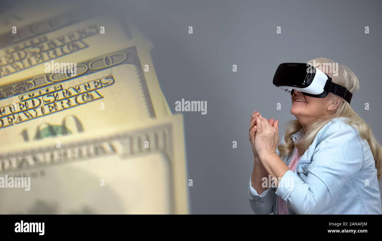 Ältere Dame tragen VR-Headset zufrieden mit Dollar Banknoten, Lotterie Konzept Stockfoto