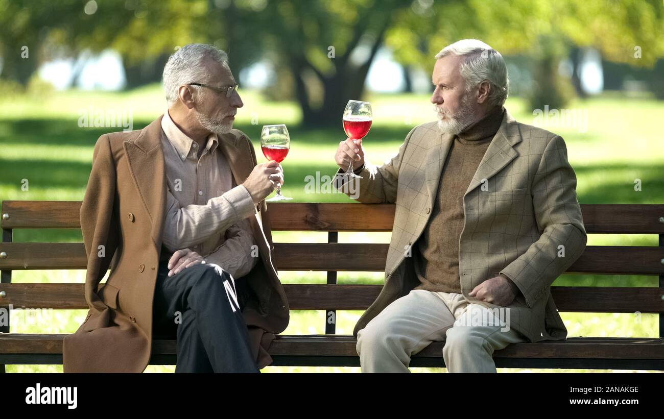 Zwei elegante älteren Herren klirren Gläser Wein im Park, alte Freundschaft Stockfoto