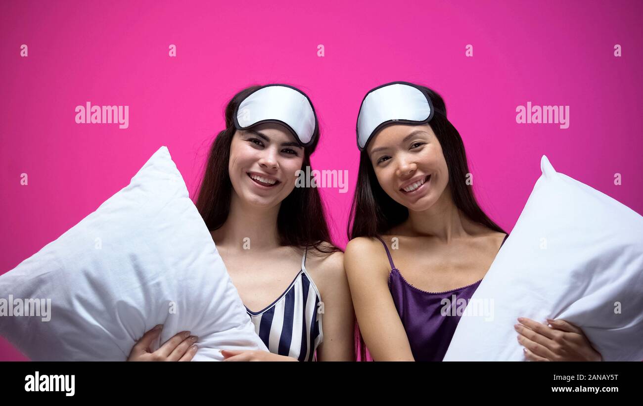 Lächelnde Frauen in den Schlaf tragen und Augenmasken holding Kissen, Pyjama Party Stockfoto