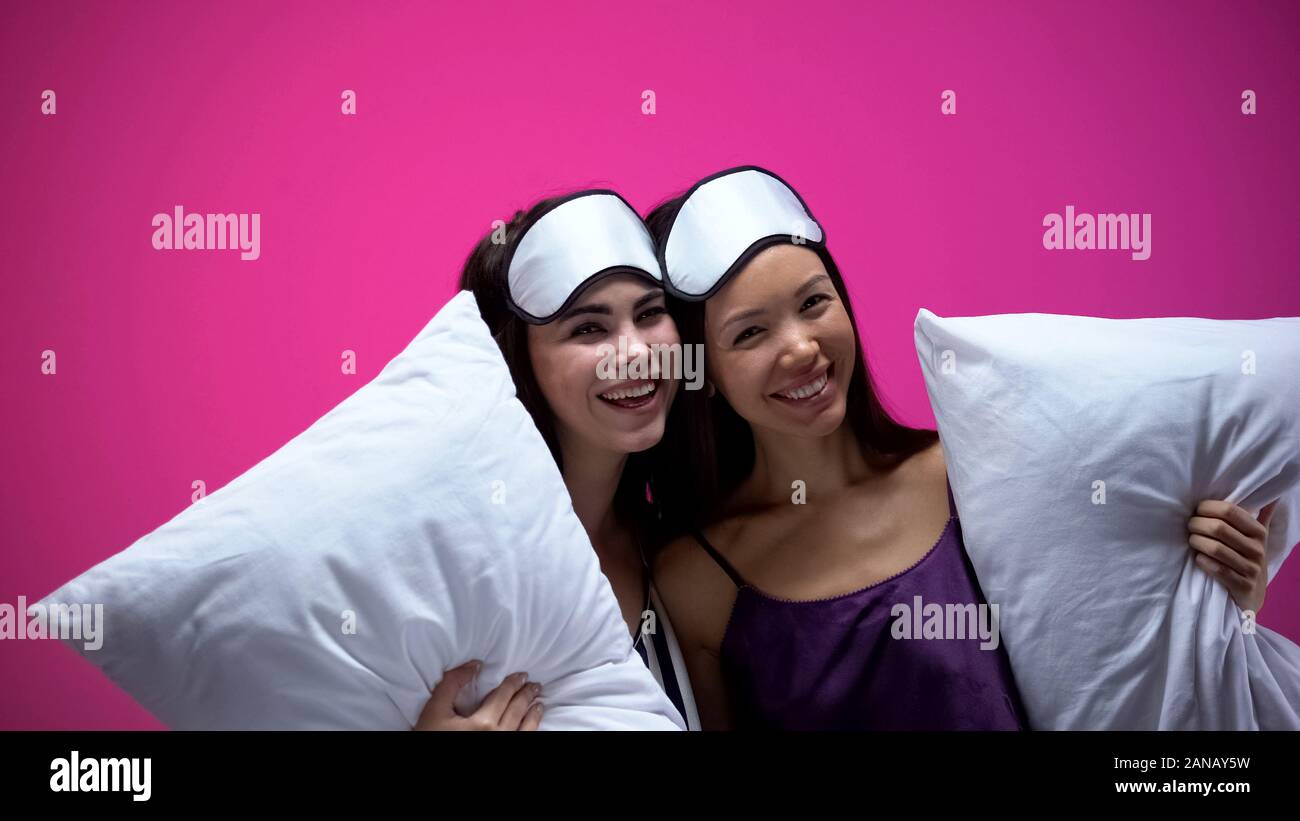 Zwei Damen in Schlafanzug und Augenmasken holding Kissen, umarmen und Lachen, rest Stockfoto