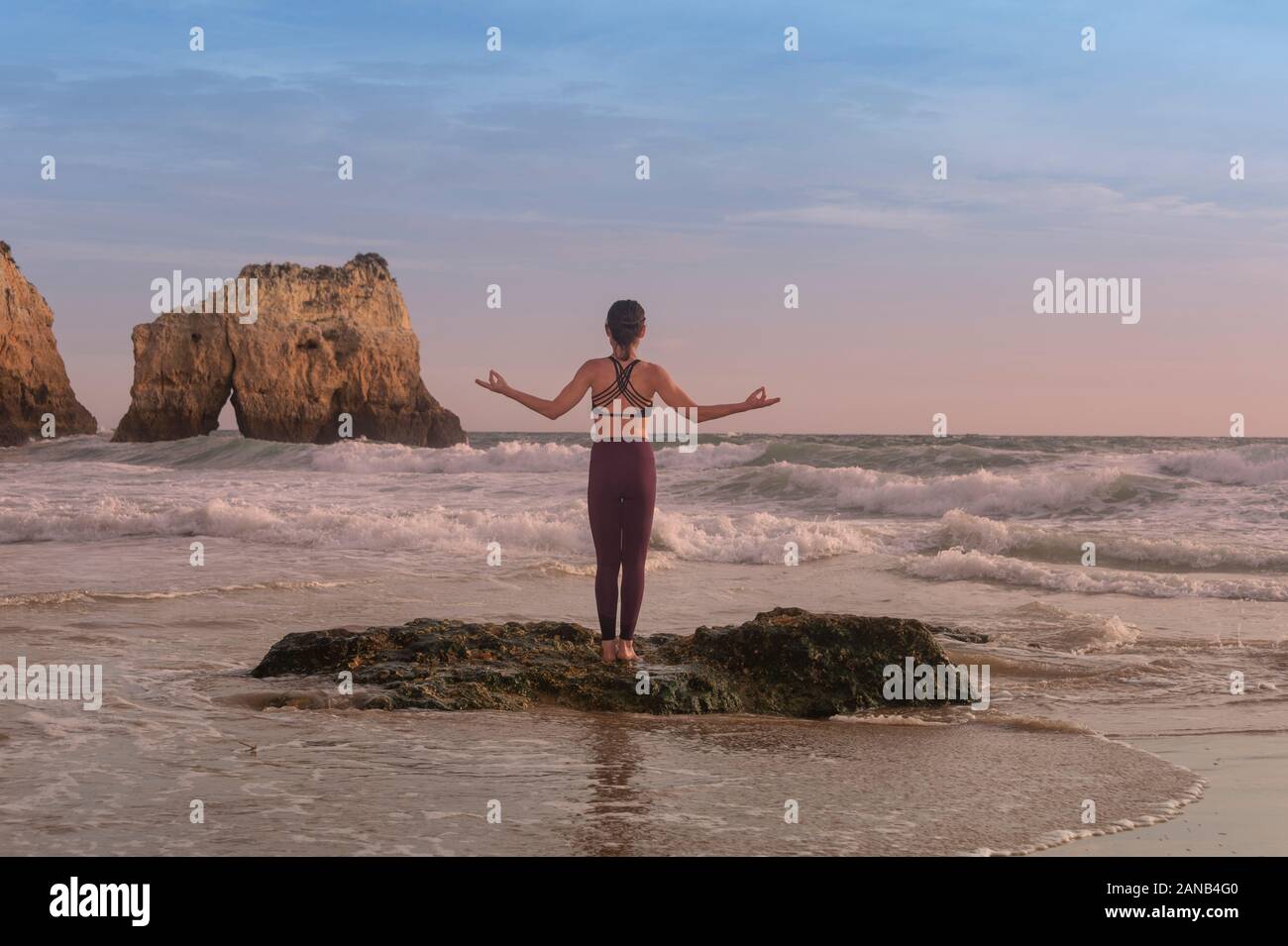 Frau Yoga steht auf einem Felsen am Meer mit Wellen, stehende Yoga dar. Stockfoto