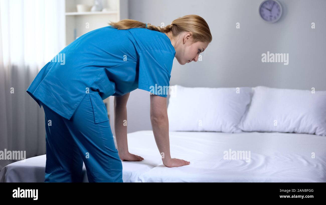 Junge Krankenschwester Vorbereitung saubere Bettwäsche in der Rehabilitation Center, guter Service Stockfoto