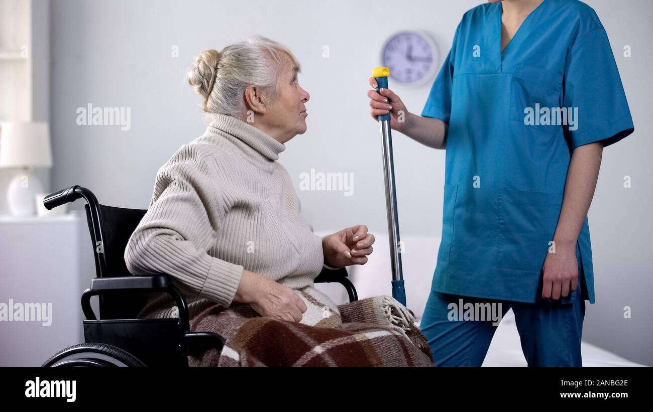 Gesprächig alte Dame im Rollstuhl klatschen mit Krankenhaus Hausmeister, Einsamkeit Stockfoto