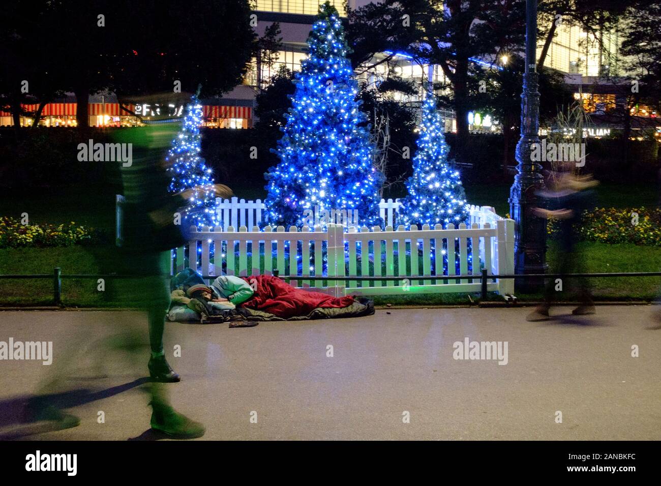 Ein Obdachloser schläft neben einem Weihnachtsbaum in Bournemouth's Winter Gardens Stockfoto