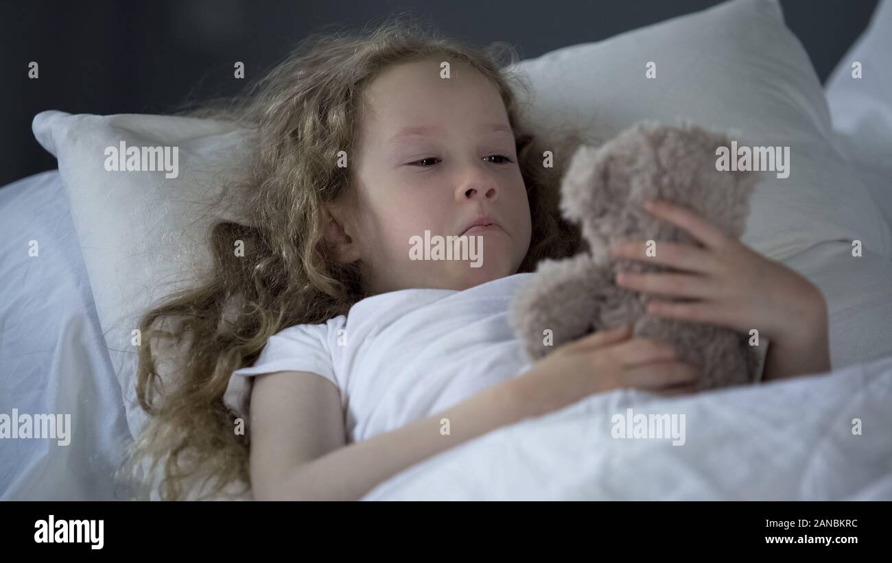 Miserable kleines Mädchen im Bett allein liegen, mit Augen voller Tränen, fehlende Mumie Stockfoto