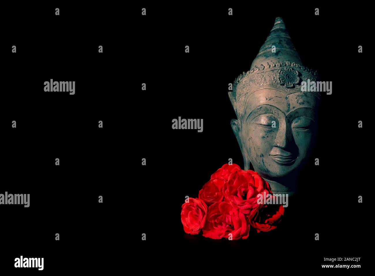 Frieden und Liebe. Traditionelle Meditation Buddha Kopf mit roten Rosen isoliert auf schwarzen Hintergrund Copyspace. Wunderschönes friedliches Bild. Ruhigen buddhistischen Geist Stockfoto