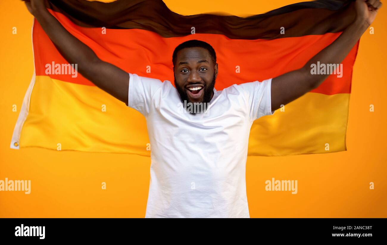 Lächelnd schwarzer Mann mit deutschen Fahne Zujubeln für nationale sport team Sieg Stockfoto
