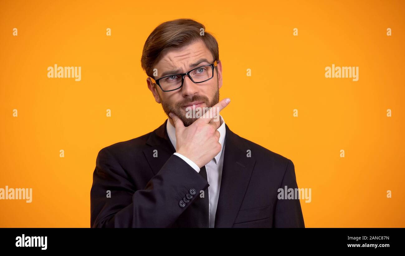 Geschäftsmann kratzen Kinn denken über Start-up-Strategie, orange Hintergrund Stockfoto