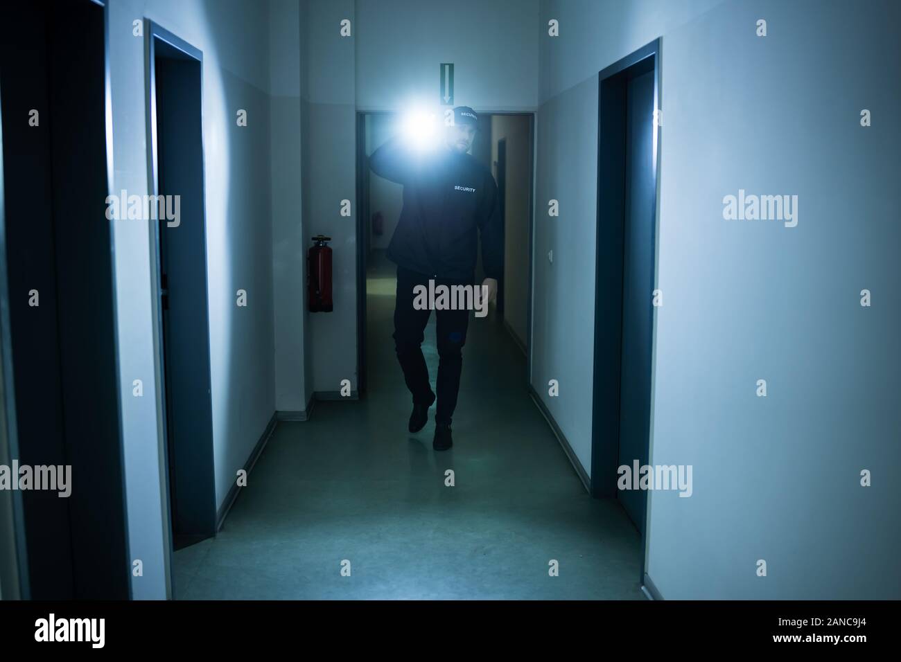 Security Guard mit Taschenlampe Wandern in Gebäude Korridor Stockfoto