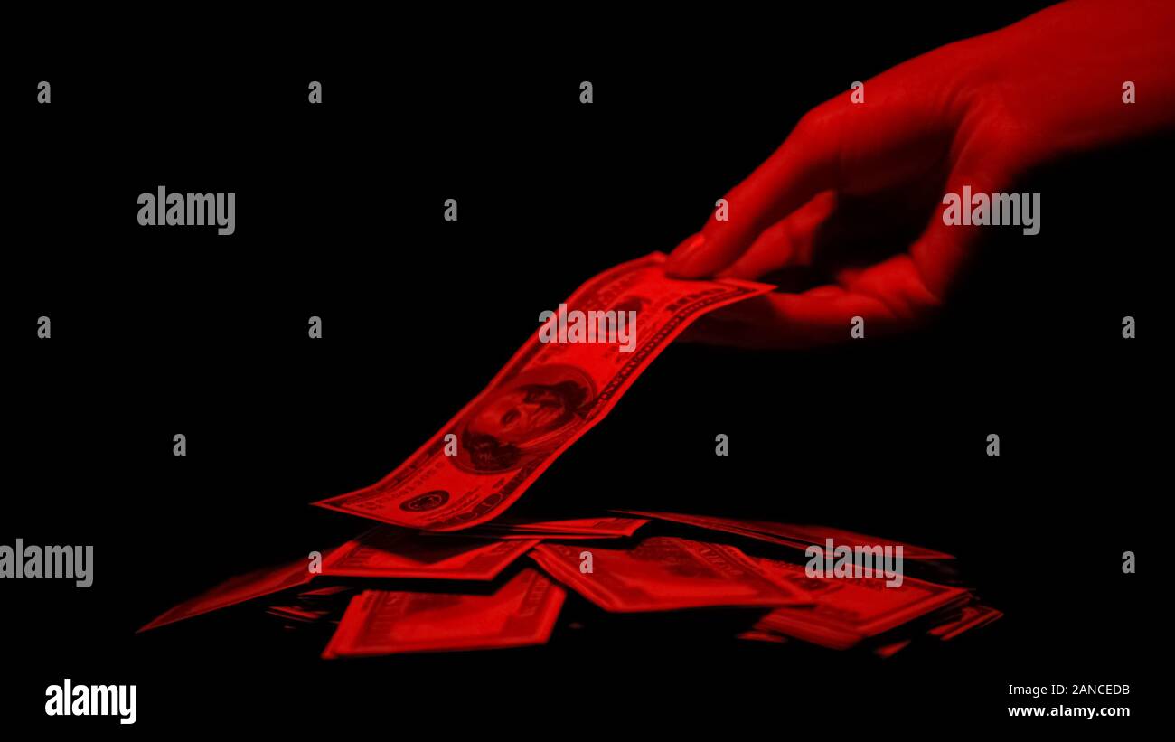 Hand dollar von Haufen durch das rote Licht leuchtet, blutige Geld Kriminalität Belohnung Stockfoto