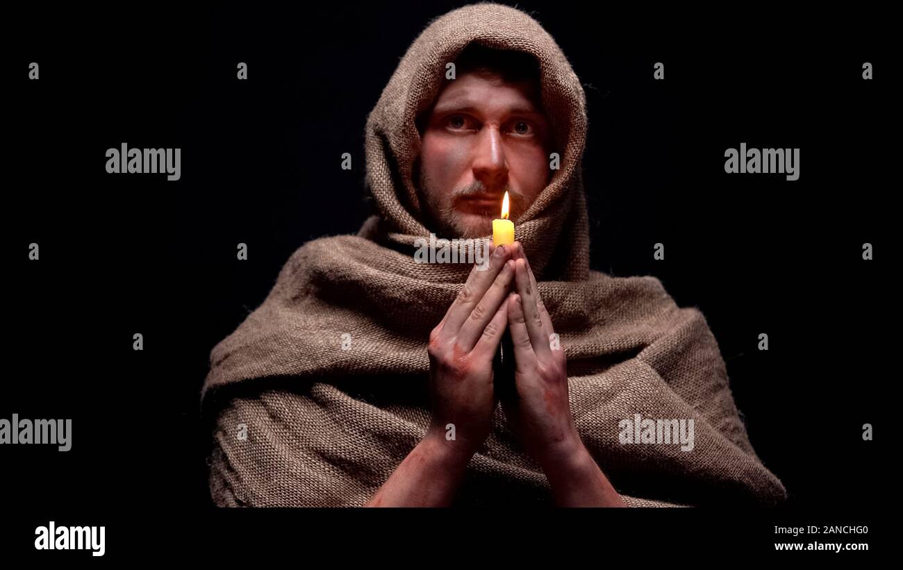 Armen kranken Mann in Robe holding Kerze beten und Gott um Hilfe zu bitten, der Glaube Stockfoto