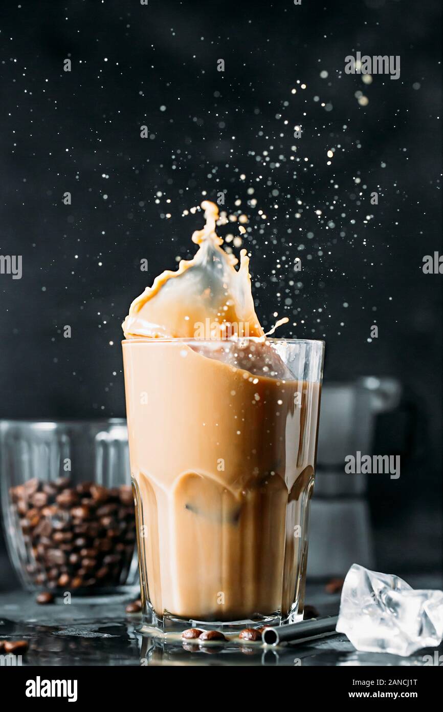 Spritzen der Eiskaffee in hohes Glas und Kaffeebohnen Stockfotografie