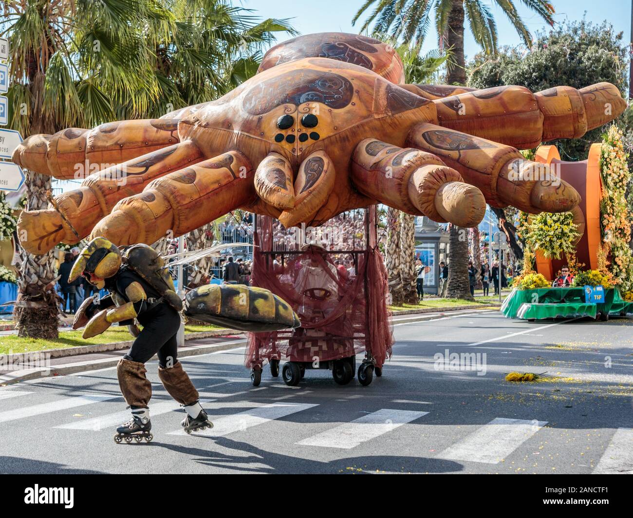 Darsteller, die als Biene gekleidet sind und einen riesigen Spinnenballon auf der Blumenparade, dem Karneval in Nizza, an der französischen Riviera, Cote d'Azur, ziehen. Stockfoto