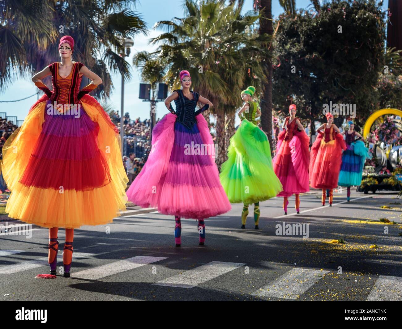 Künstler in bunten Kleidern und Stelzen bei der Blumenparade, im Karneval von Nizza, an der französischen Riviera, an der Cote d'Azur, Frankreich. Stockfoto