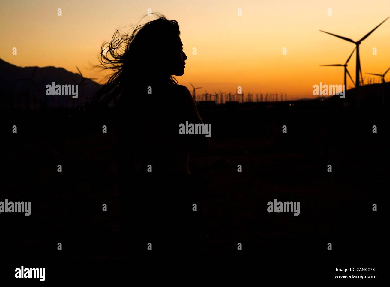 Silhouette der Frau vor dem Windpark bei Sonnenuntergang Stockfoto