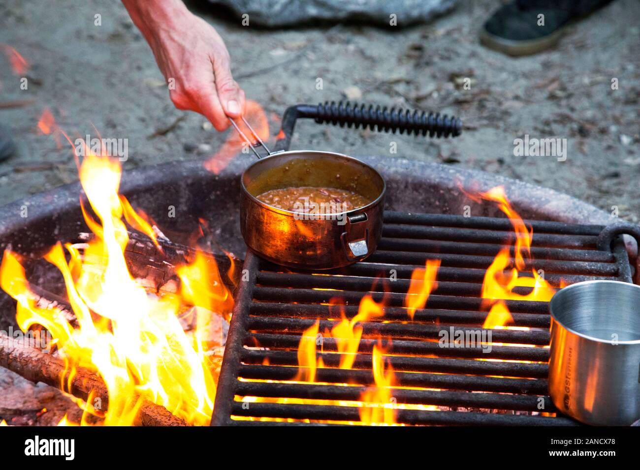 Holz Lagerfeuer mit Person Kochen Stockfoto