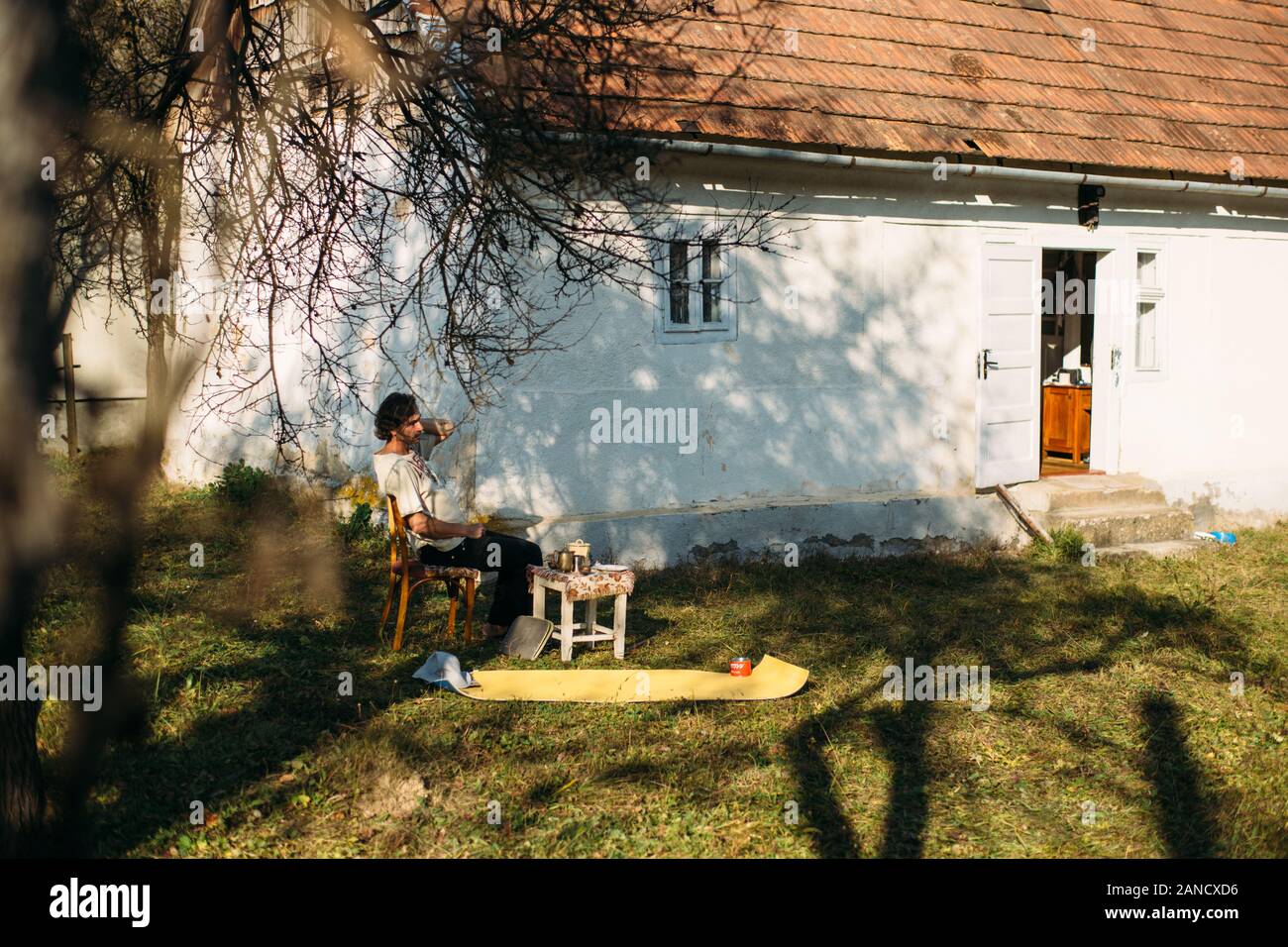 Ein Mann sitzt vor seinem Haus in einem kleinen Dorf Stockfoto