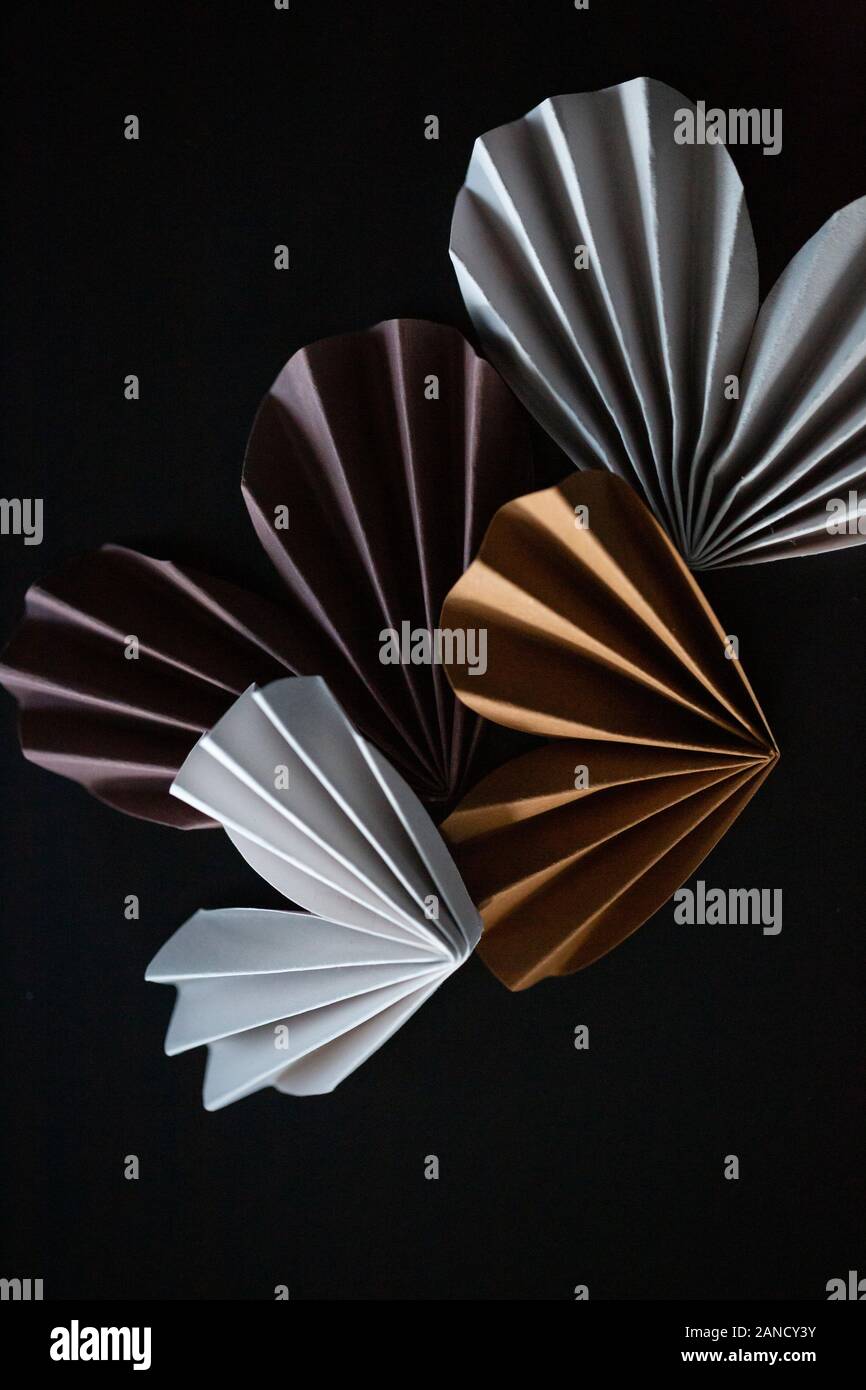 Neutral gefärbte Papier Origami Herzen vor schwarzem Hintergrund Stockfoto