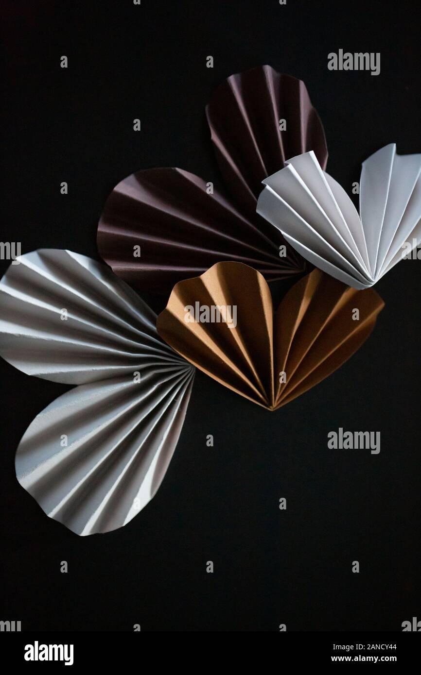 Nahaufnahme von neutralen farbigen Papier Origami Herzen auf dunklem Hintergrund Stockfoto