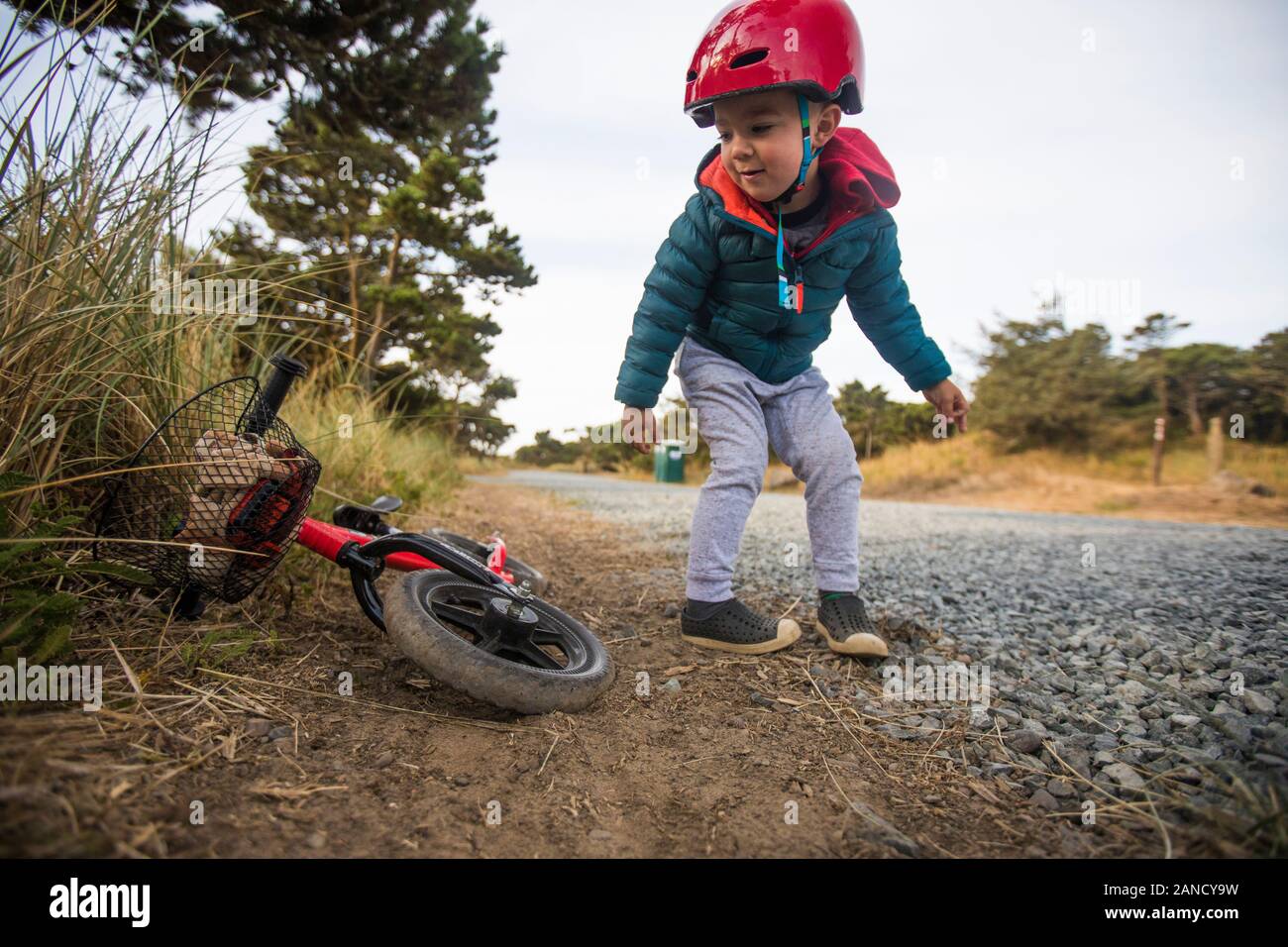 Kleinkind Junge lehnt sich rüber, um Fahrrad zu holen. Stockfoto