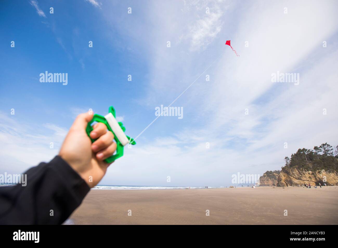 Menschliche Hand hält sich am Strand an den roten Drachen. Stockfoto