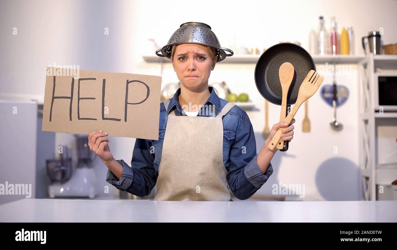 Unerfahrene Hausfrau bittet um Hilfe beim Kochen, das Tragen von Topf am Kopf, Witz Stockfoto