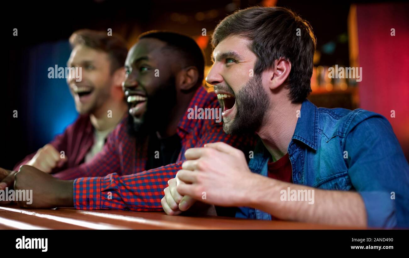 Fröhliche multirassischen Freunde schreien, Feiern sport team Sieg in bar Stockfoto