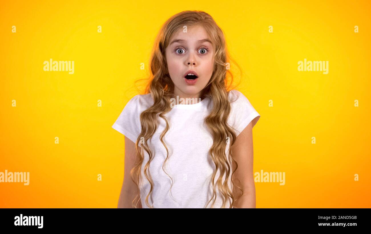 Lustige Schulmädchen mit weit geöffneten Augen auf der Suche nach Cam, schockierenden Nachrichten, Promo Stockfoto