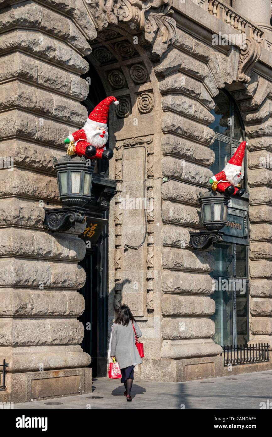 Eine Person geht in ein Gebäude, dessen Leuchten mit Santa Claus durch den Bund in Shanghai, China, 2. Dezember 2019 eingerichtet. 20 Santa Claus Zahlen Stockfoto