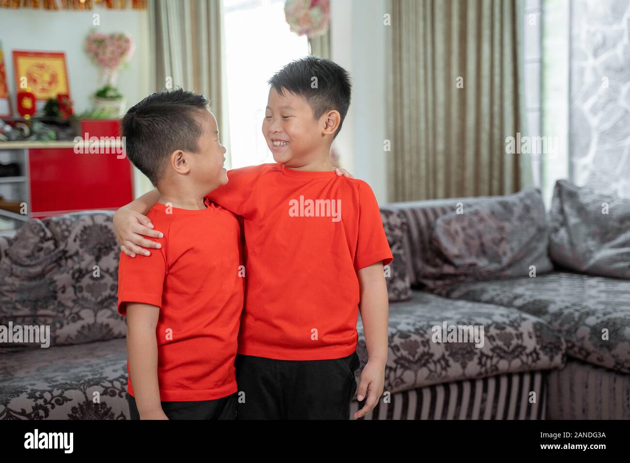 Zwei Kinder lächeln einander in roten Hemden Stockfoto