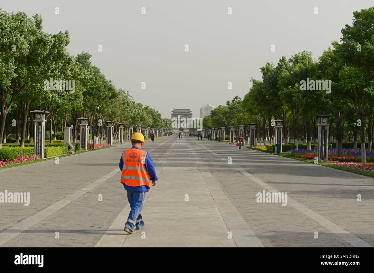 Handwerker in reflektierende Jacke und harte Sicherheit hat Spaziergänge in einer verkehrsberuhigten Garten von Yongdingmen Tor in der Ferne. Peking, China Stockfoto