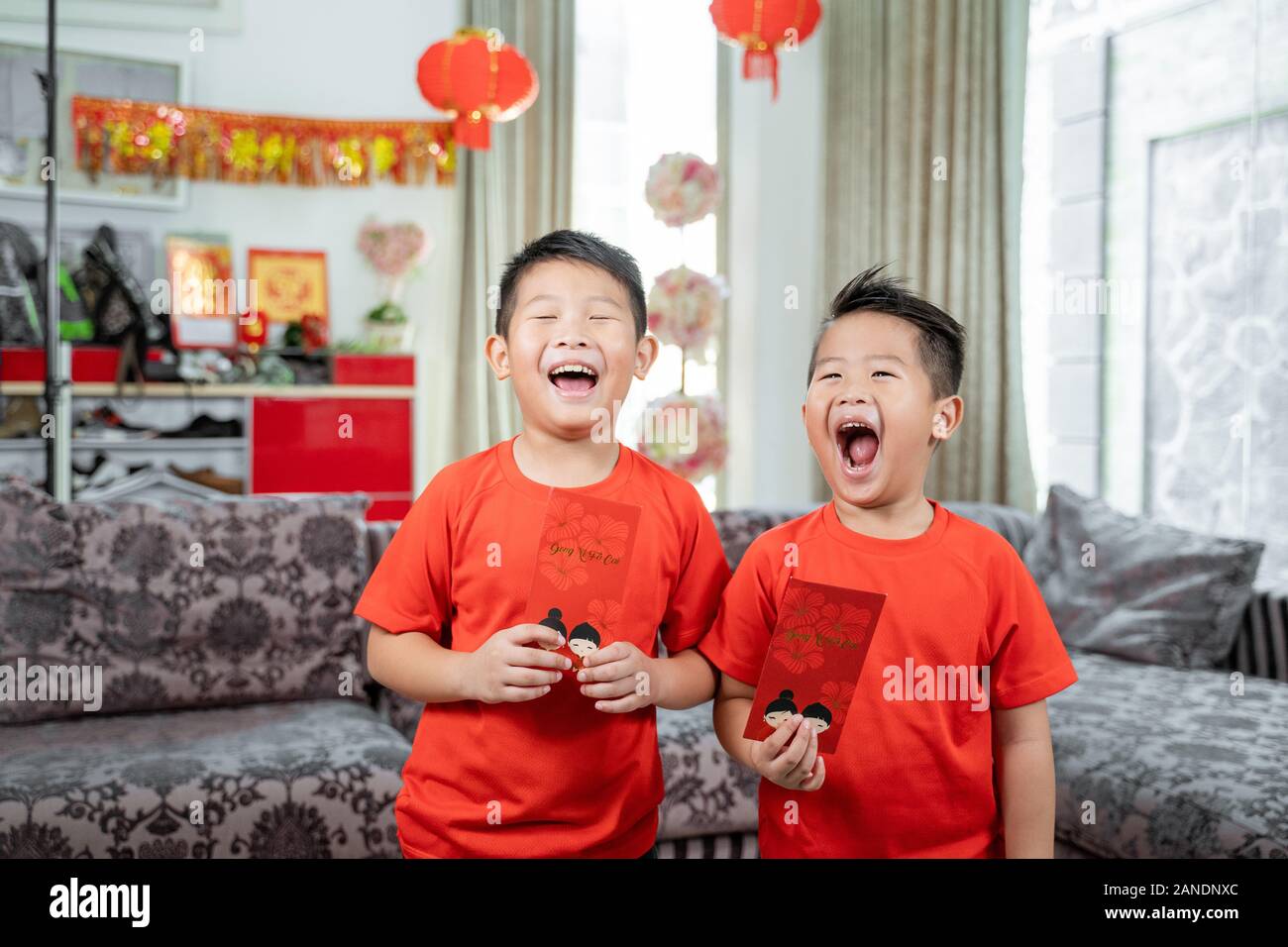 Zwei Kinder lächeln in roten Hemden mit angpau Stockfoto