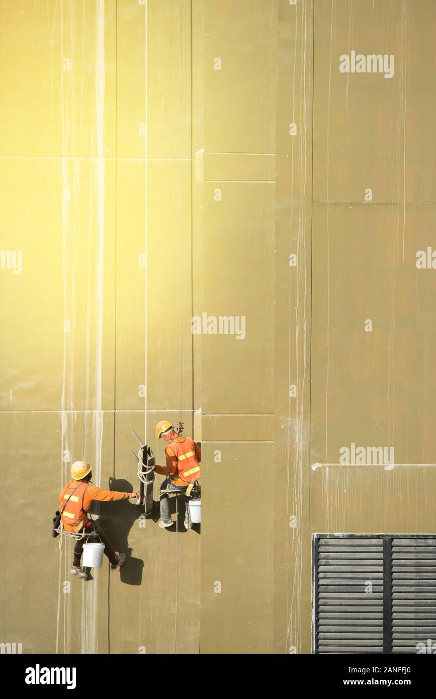Arbeitnehmer engagieren sich ihre Jobs auf dem hohen Gebäude wie die Sonne Licht an der Wand. Stockfoto